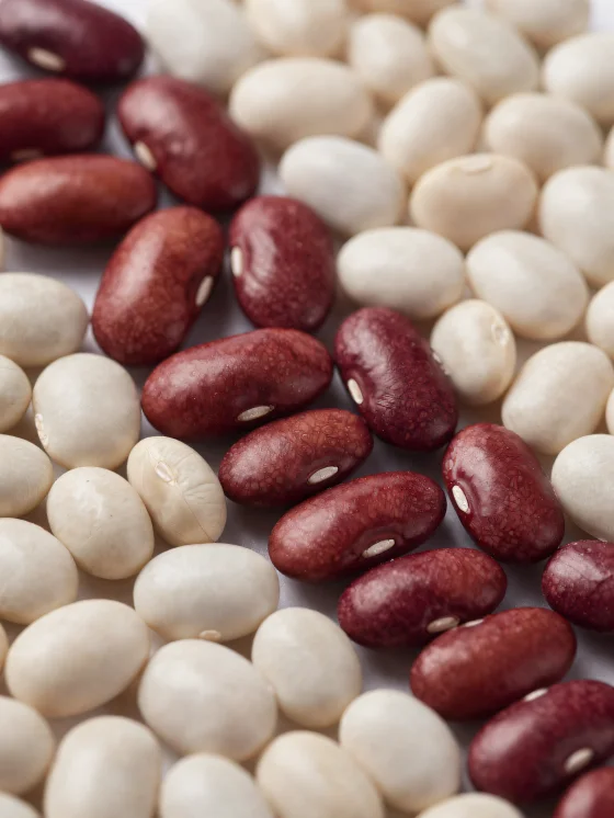 Various types of dried beans on a wooden table, in bowls and scattered