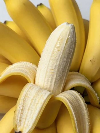 Fresh banana whole and sliced, in a bowl and on a rustic table