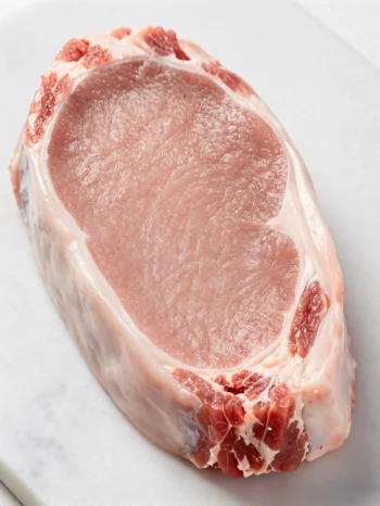 Fresh pale veal cuts with spices on a wooden chopping board