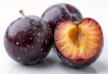 Fresh purple plums halved and whole, with homemade jam on a rustic table