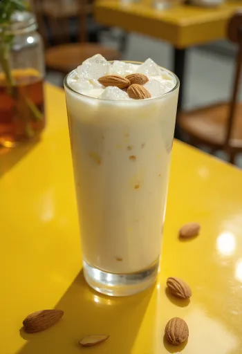 Almond lassi in a glass, garnished with ice cubes and almonds