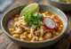 Pozole de pollo with chicken and hominy corn, lime wedges