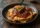 Chilaquiles with pasilla chilli sauce – with red sauce, crispy tortilla pieces, grated cheese and sour cream